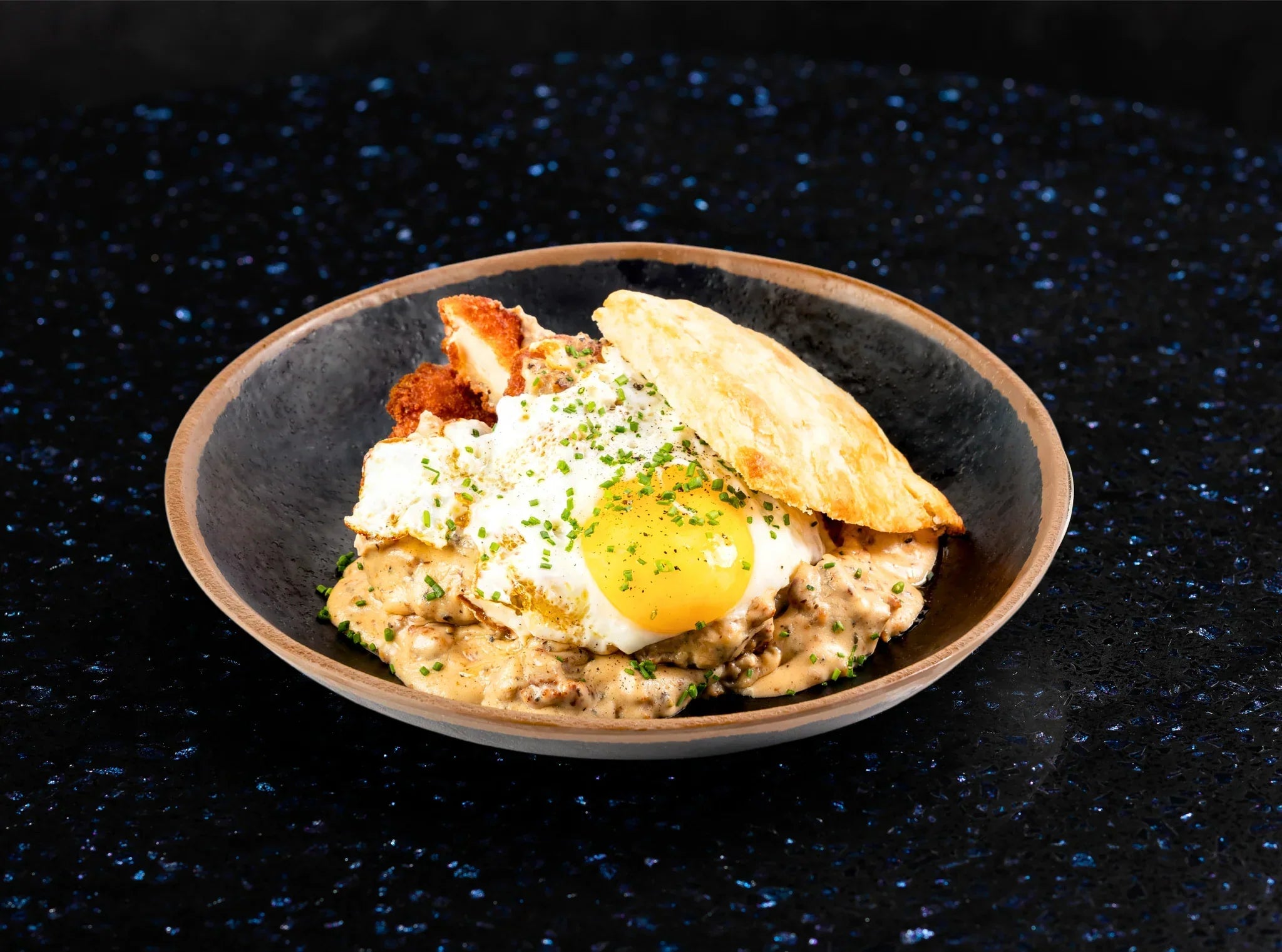 Crispy fried chicken on top of golden waffles, drizzled with spicy maple syrup and garnished with fresh herbs.