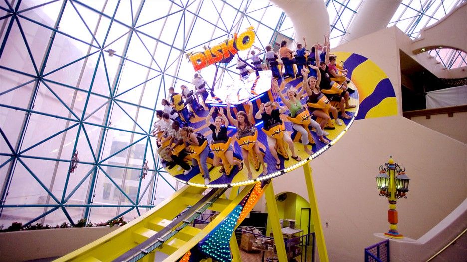 Atomic Golf’s high-tech golf bays alongside an amusement park roller coaster.
