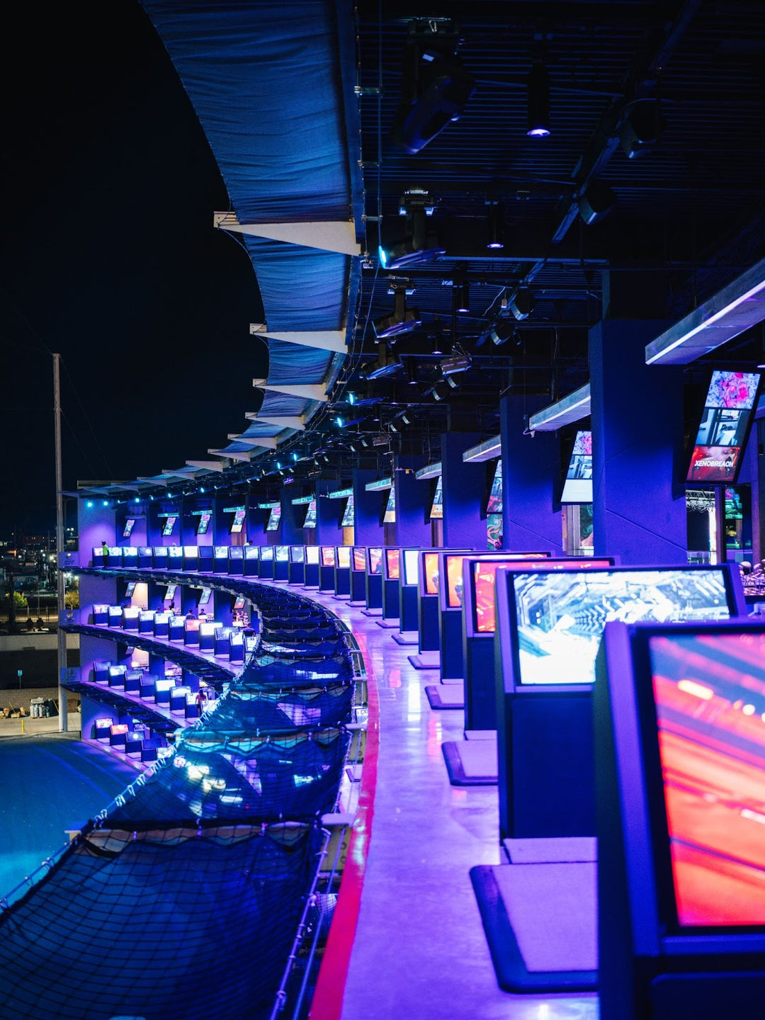 A golfer enjoying a swing at Atomic Golf in Las Vegas with a vibrant atmosphere.